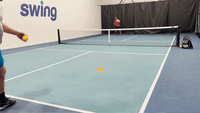 Player at baseline hitting a crosscourt return to opponent at the net during an indoor pickleball drill