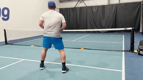 Pickleball player dinking crosscourt and recovering toward the kitchen on an indoor court
