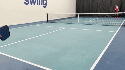 Two players on an indoor pickleball court practicing a serve, return, and drop shot sequence showing court positions and movement