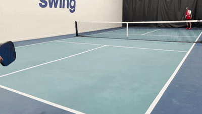 Two players on an indoor pickleball court practicing a serve, return, and drop shot sequence showing court positions and movement