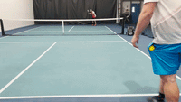 Two pickleball players demonstrating a sidespin groundstroke on an indoor court, one player at the net preparing to volley