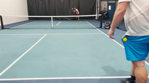 Two pickleball players demonstrating a sidespin groundstroke on an indoor court, one player at the net preparing to volley