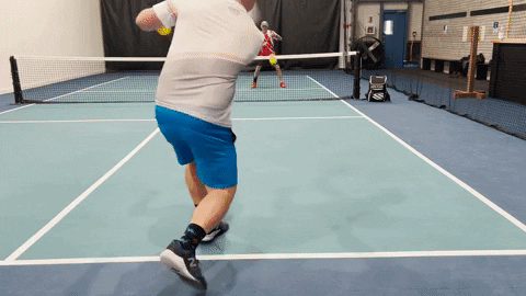 Pickleball player volleying at the net returning a driven shot on an indoor court